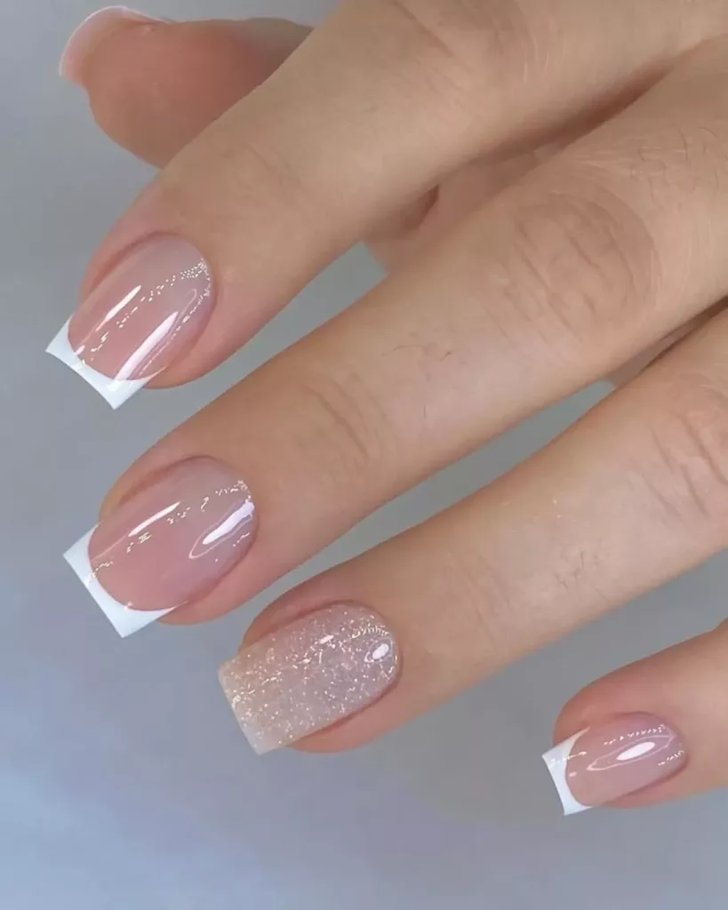 Unhas com francesinha tradicional e destaque em glitter rosé no dedo anelar, combinando elegância e brilho.