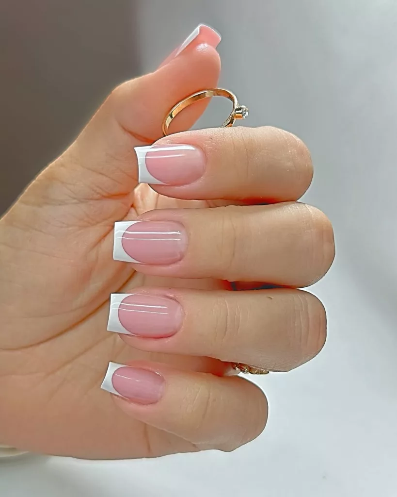 Unhas com francesinha perfeita e base transparente rosada, acabamento brilhante e elegante.