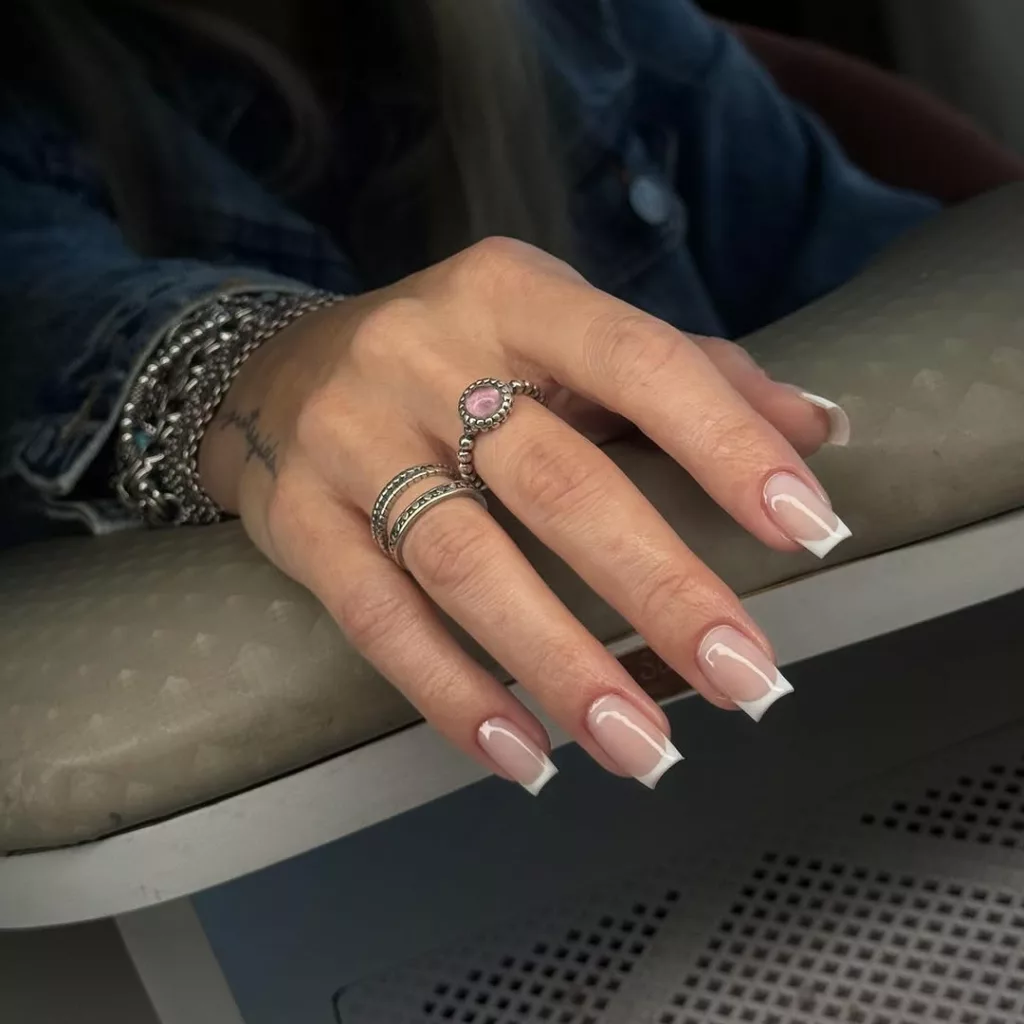 Francesinha tradicional em unhas quadradas médias com brilho delicado, realçando acessórios prateados e anel com pedra rosa.