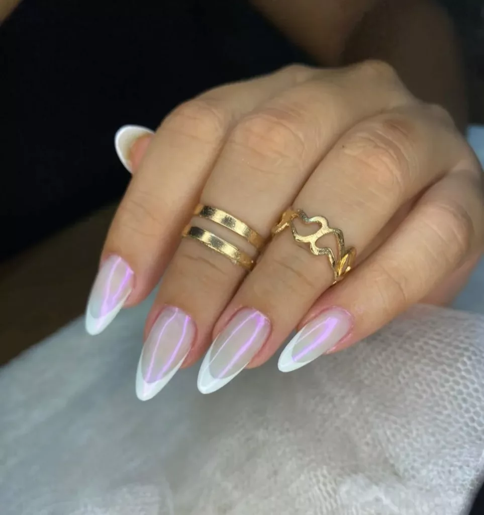 Francesinha stiletto com ponta branca fina e base com reflexo perolado e brilho holográfico, decoradas com anéis dourados.