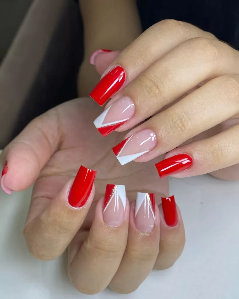 Unhas decoradas para o Natal com esmalte vermelho e francesinha diagonal em branco, criando um visual moderno e geométrico com toque festivo.
