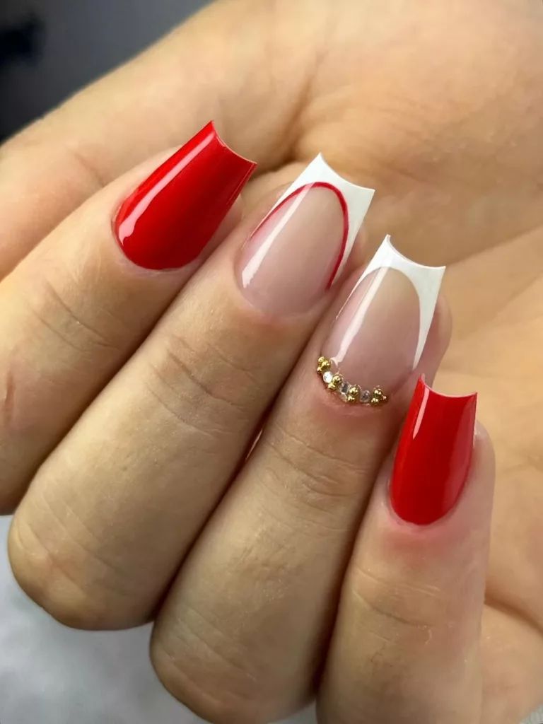 Unhas de Natal com francesinha vermelha moderna sobre base nude e detalhe delicado em pedrarias.