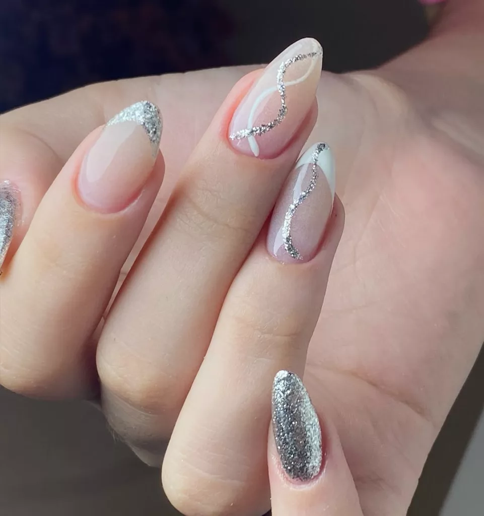 Unhas decoradas para fim de ano com desenho ondulado em glitter prata sobre esmalte nude, proposta minimalista e elegante
