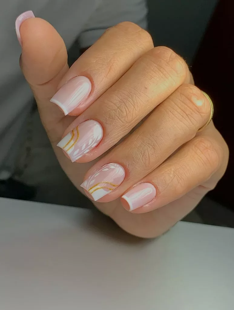 Unhas decoradas para fim de ano em tom nude claro com francesinha branca e detalhes dourados, visual clean e sofisticado