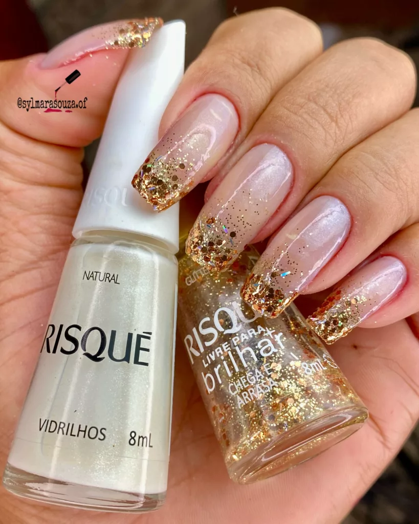 Unhas de Ano Novo com base nude leitosa e francesinha invertida em glitter dourado, criando efeito degradê elegante e sofisticado nas pontas.