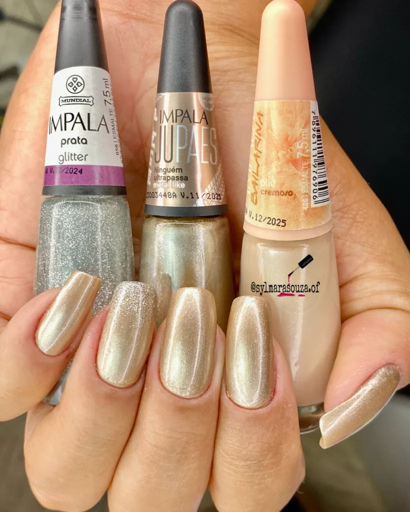 Unhas em tom champagne metálico com acabamento uniforme e detalhe em glitter prateado, trazendo efeito luxuoso e refinado para o Ano Novo.