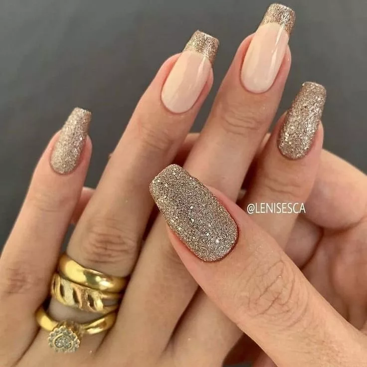 Unhas longas com glitter champagne, combinando acabamento completo em alguns dedos e francesinha brilhante em outros, criando um visual glamouroso.