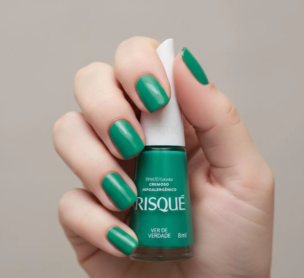 Unhas com esmalte vermelho cremoso vibrante Ana Hickmann Lady Poderosa, acabamento uniforme e marcante, segurando o frasco do esmalte, clássico elegante para o Natal e ocasiões festivas.