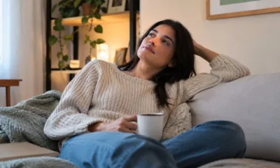 mulher sofa cha cafe pensando - Você sente culpa quando decide descansar? Entenda por que o lazer virou obrigação e o ócio pesa na consciência
