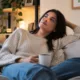 mulher sofa cha cafe pensando - Você sente culpa quando decide descansar? Entenda por que o lazer virou obrigação e o ócio pesa na consciência